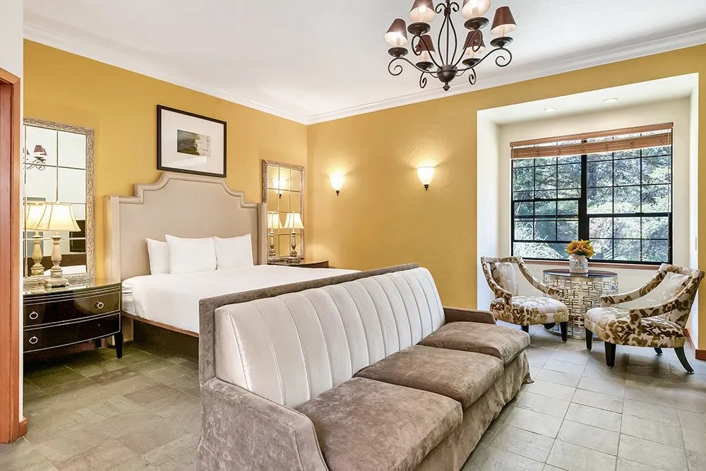 A king bedroom with cream walls and a vaulted beamed ceiling
